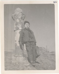 Boy with stone pillar at burial site