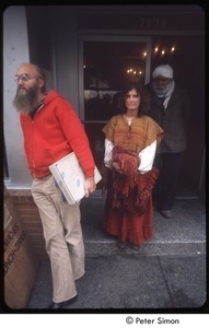 Ram Dass holding a box labeled 'The Path Book,' Cathy Brown and a man in a turban stand behind