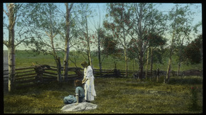 Two young woman in fenced in field near poplars