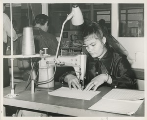 A woman practices using a sewing machine at TOWER training