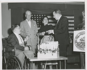 Bruce Barton and an unidentified man handing scrolls to a man in a wheelchair and a woman with forearm crutches at an ICD event