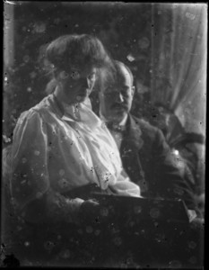 Woman seated on man's lap, holding book