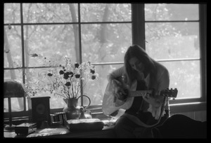 Judy Collins playing guitar while silhouetted against a window in Joni Mitchell's house in Laurel Canyon