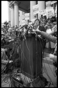 Gary Hart at a microphone-encrusted podium, addressing an crowd after renewing his bid for the Democratic nomination for the presidency