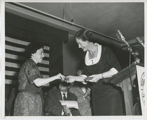 Unidentified staff member handing gift to client on stage at Institute Day