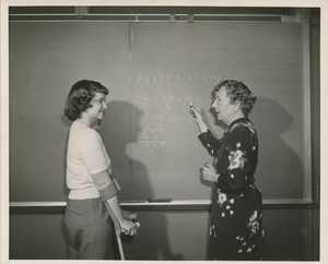 Miss R.L. Brady teaching math to a young woman using forearm crutches