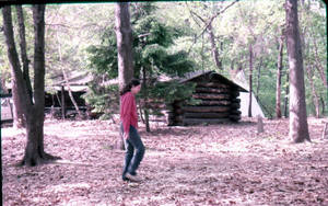 Student walking by log cabin at East Campus