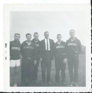 Roger Maloney standing with coach Vernon Cox and track teammates (December, 1958)