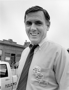Mayor Raymond L. Flynn wearing Dudely Street Neighborhood Initiative pins and standing in front of a Boston Public Works truck