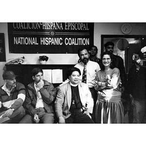 Clara Garcia with several men, including a clergyman, posing under a banner for the National Hispanic Coalition.