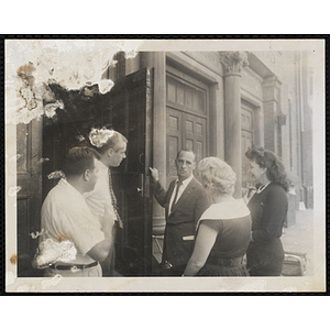 A Boys' Club staff member opens a door while talking to four people surrounding him