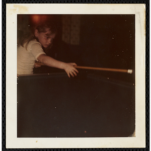 A girl holding a cue across the pool table in the South Boston Boys' Club