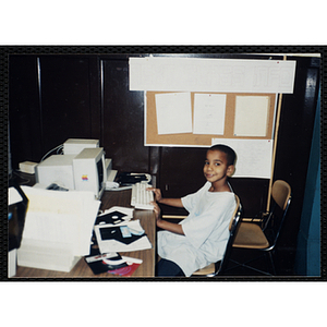 A boy sits at a Macintosh computer in a lab