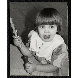 A Girl sitting at a table and holding stacking toys