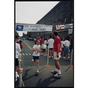 A girl runs past spectators during the Battle of Bunker Hill Road Race