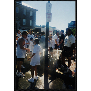 A man cools a girl with water from a hose during the Battle of Bunker Hill Road Race