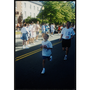 A boy and a man run in the Battle of Bunker Hill Road Race