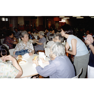 Woman holds a microphone for a woman to speak during a Chinese Resident Association meeting