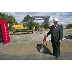 George J. Kostas stands with a shovel at the construction site for the George J. Kostas Research Institute for Homeland Security during the groundbreaking ceremony
