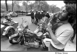 Elliot Blinder nuzzling a puppy and standing by parked Boston Police motorcycles