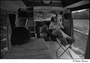 Ram Dass in his van: Ram Dass reading, seated with his feet up