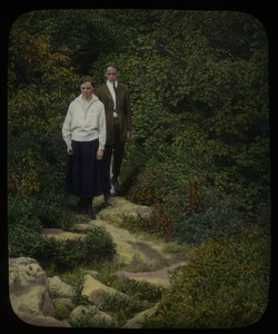 Boy and girl on rocky path surrounded by trees and shrubs