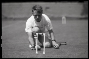 Croquet player kneeling on the ground to line up a shot through a wicket, Newport, R.I.