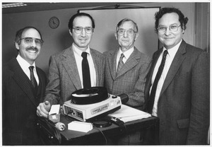 Henry Nelson Little standing indoors with group of former students