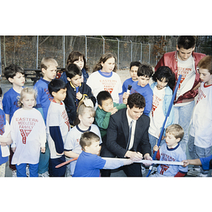 Children watching a man sign a hockey stick outside the Eastern Middlesex Family YMCA