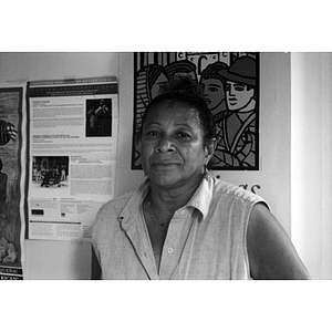 Woman in a sleeveless blouse standing in front of a poster.