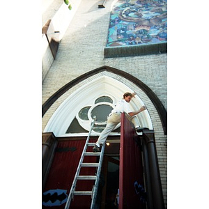 Volunteer on a ladder at the Jorge Hernandez Cultural Center entrance.