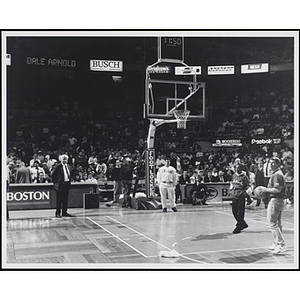 Boston radio personality Dale Arnold, at far right, turns his back with a basketball before throwing it, while the spectators look on, at a fund-raising event held by the Boys and Girls Clubs of Boston and Boston Celtics