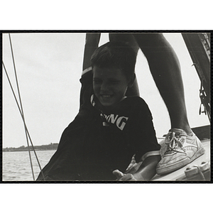 A man holds a boy over the side of a sailboat in Boston Harbor