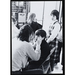 A woman paints a boy's face during a party