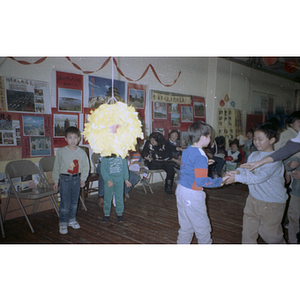 Boy hands a stick to another boy so he can take a swing at a piñata