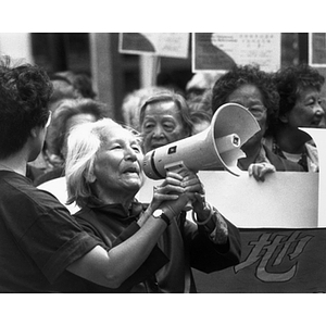 Older Chinese woman speaks into a bullhorn at a demonstration protesting the New England Medical Center's proposal to build a garage on Parcel C in Chinatown