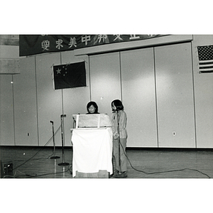 Two Chinese woman speak in the Josiah Quincy School auditorium at an event about the normalization of U.S. and China relations