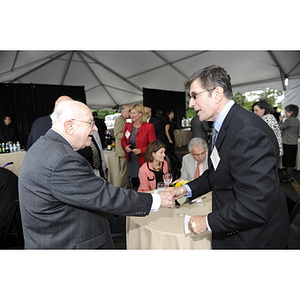 Dr. George J. Kostas shakes hands with James Kaldaxis at the groundbreaking ceremony for the George J. Kostas Research Institute for Homeland Security