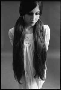 Three quarter-length studio portrait of a model in a loose-fitting shift, head slightly bowed