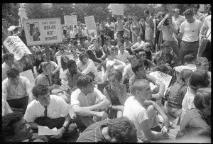 Anti-Vietnam war protesters sitting down after Assembly of Unrepresented People peace march, raising signs 'They need bread not bombs'