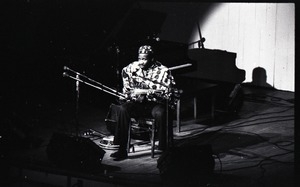 Taj Mahal in concert at Northfield, Mass.: Taj Mahal seated, playing steel guitar