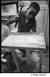Boy hammering a nail into wood, Liberation School, Boston, Mass.