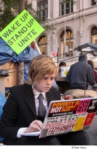 Occupy Wall Street: demonstrator in a suit using a bumper sticker-covered laptop