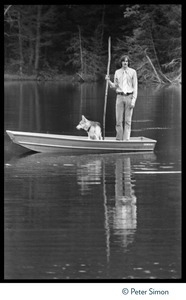 James Taylor standing in a row boat in a pond at Tree Frog Farm commune, with stick and dog