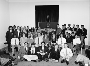Congressman John W. Olver (center) with a group of visitors to the capitol, seated in front of a UMass Amherst banner