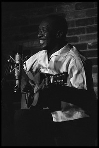 Josh White performing on guitar in a coffeehouse