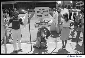 Protesters associated with Mobilization for Survival at an antinuclear demonstration near Draper Laboratory, MIT, carrying a sign reading 'Feed the cities and not the monster of nuclear power and arms'