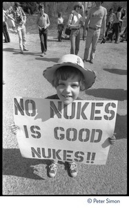Child holding a sign reading 'No nukes is good nukes,' during the occupation of Seabrook Nuclear Power Plant