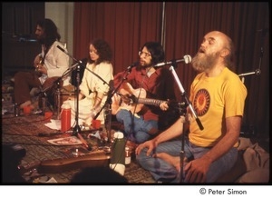 Ram Dass singing, on stage with Amazing Grace