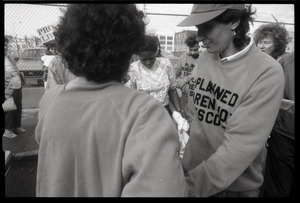 Escorts ushering a woman into the Planned Parenthood clinic in Providence, pro-life protesters in the background